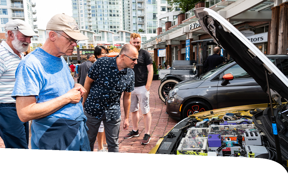 Men stare at the interior of an electric car